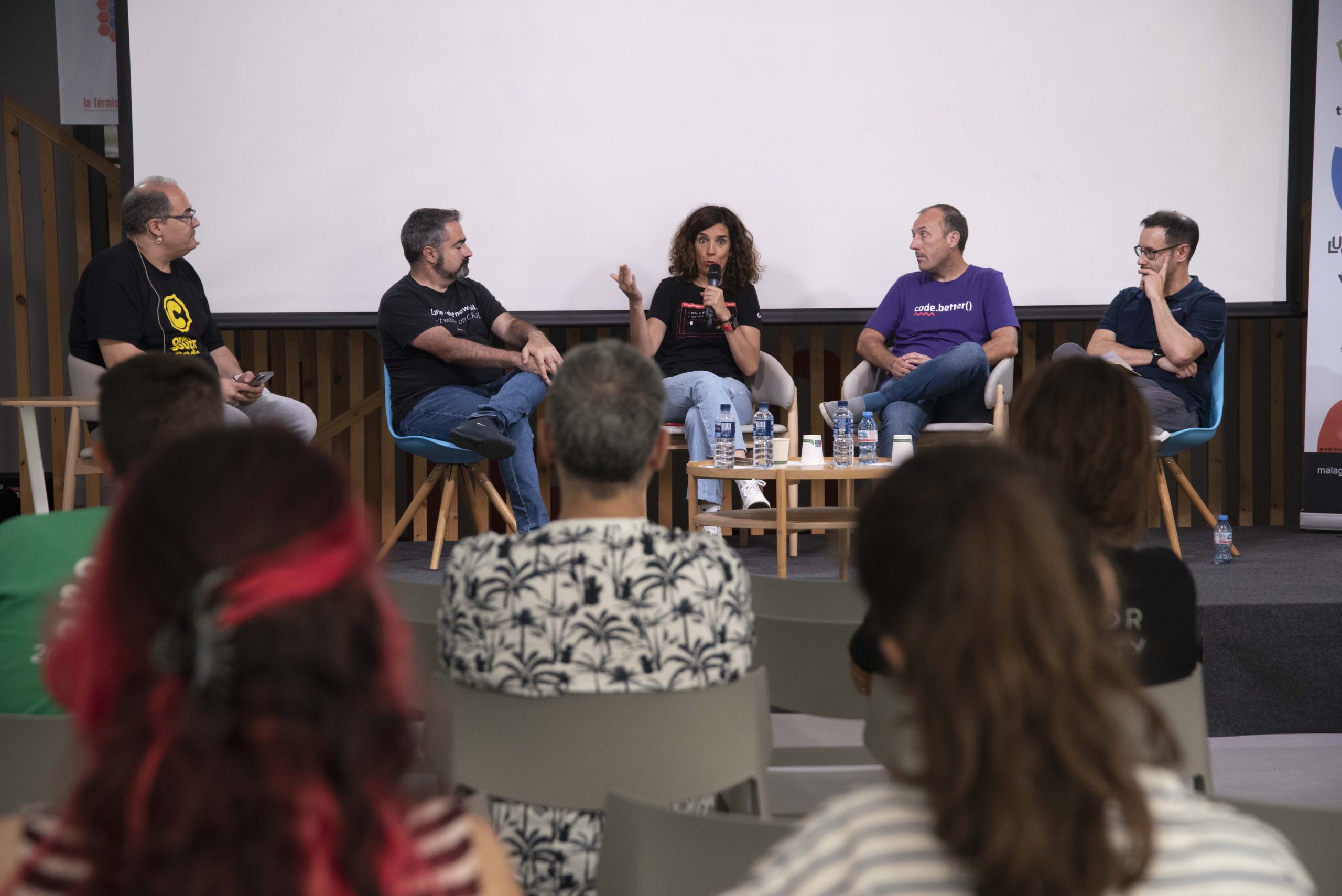 Vista de una charla de OpenSouthCode 2023 donde se ven 5 participantes en un panel de expertos sobre tecnologías modernas mientras la audiencia del mismo escucha atentamente.